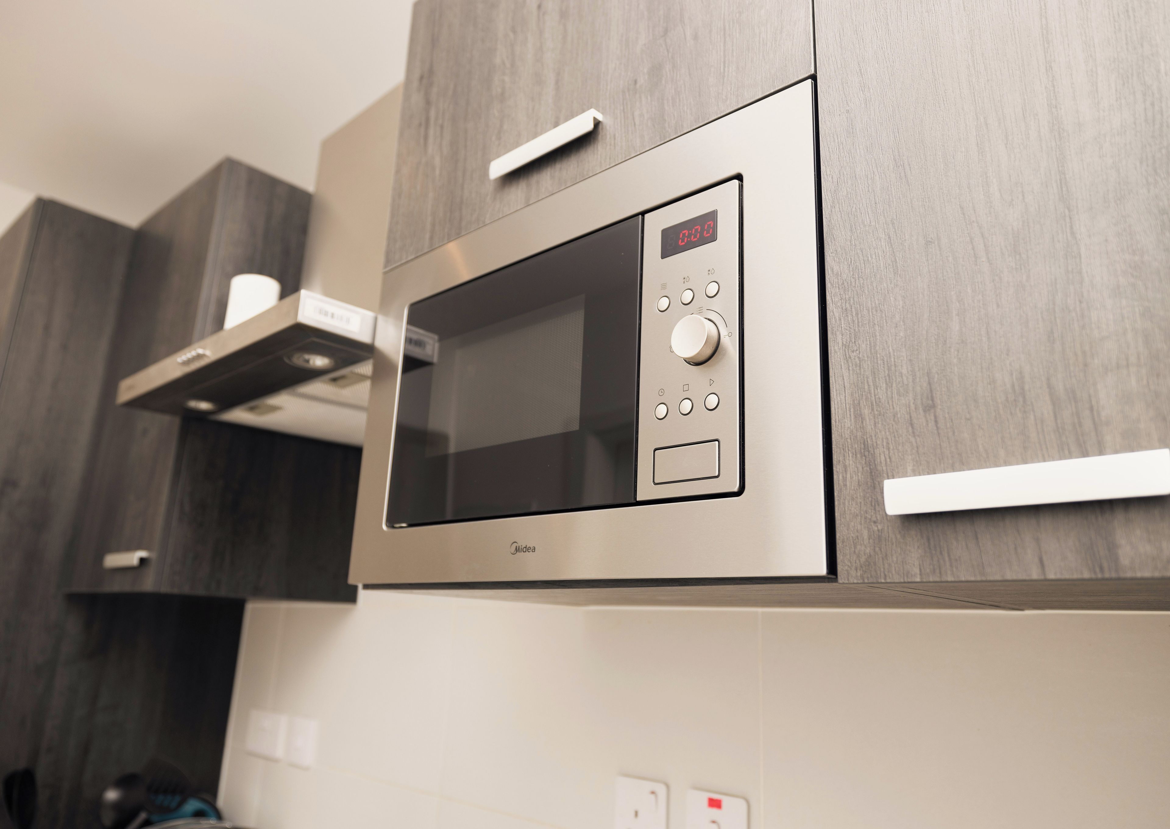 A modern kitchen with a built-in microwave oven, a digital display, and control buttons.