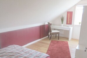 A bedroom with a bed, a desk, a chair, a window, and a plant. - Holiday home in Niesgrau with swimming pool (Niesgrau)
