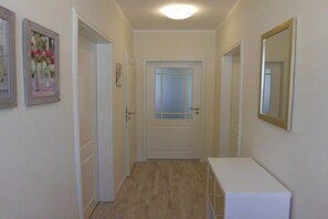 Ein Flur mit einer weißen Tür, einem Spiegel an der Wand und einem kleinen weißen Schrank.