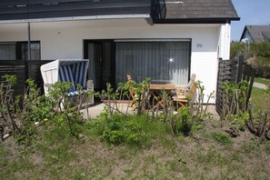 A residential property with a patio area, a wooden table, and chairs. - Holiday apartment in Sylt with 2 bedrooms (Westerland)