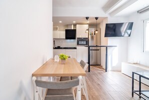 A modern kitchen with a dining table, chairs, and a TV mounted on the wall. - Cubo's Espronceda Malaga Apartment / urban / air conditioning / free wifi (Málaga)