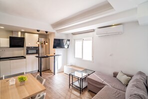 Eine moderne Küche mit Essbereich, einem Flachbildfernseher und einer Couch.