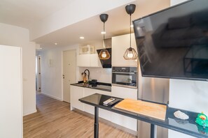 A modern kitchen with a large flat-screen TV, wooden flooring, and pendant lighting. - Cubo's Espronceda Malaga Apartment / urban / air conditioning / free wifi (Málaga)