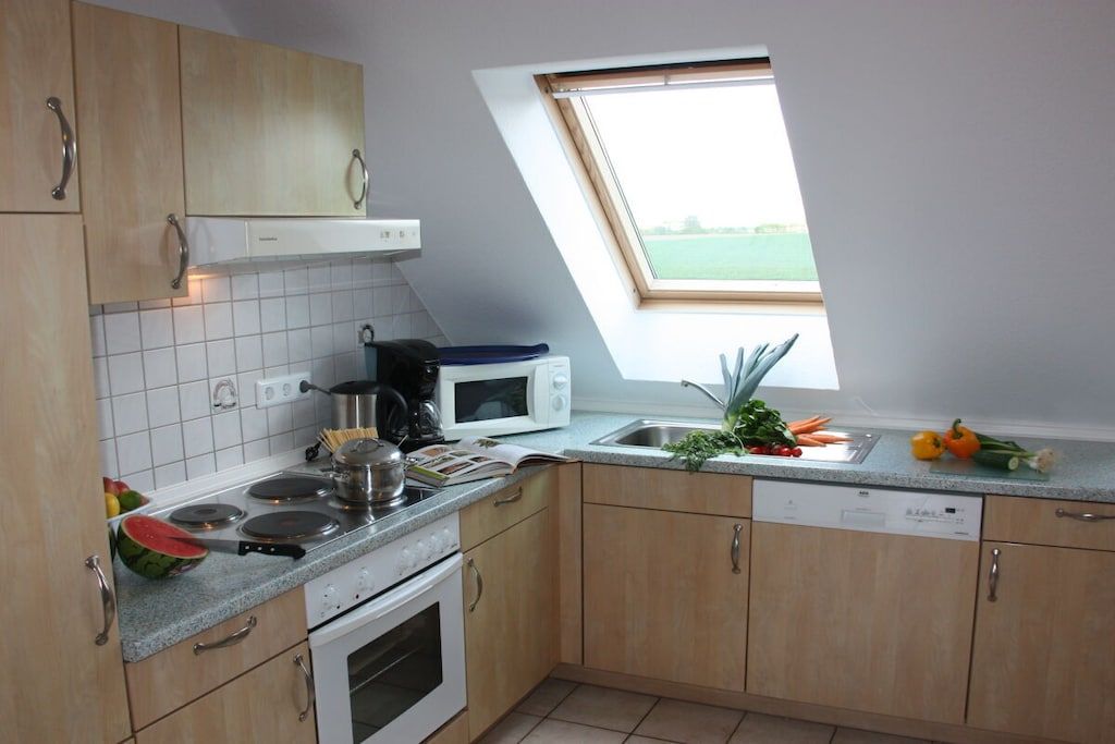 A kitchen with a microwave, stove, and sink, with a window above the sink.