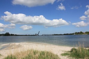 Ein Fluss mit einem Sandstrand und einer Brücke im Hintergrund.