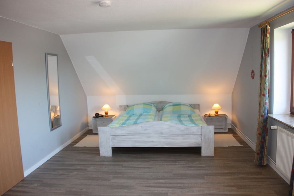 Ein Schlafzimmer mit einem Bett, zwei Nachttischlampen, einem Spiegel und einer Heizung.