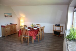 Ein Essbereich mit einem Tisch für vier Personen, Holzstühlen, einer roten Tischdecke und einer Lampe.