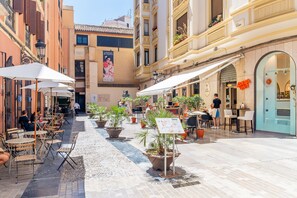 An outdoor café area with tables and chairs, potted plants, and a sign for Café Berlin. - Cubo's Montaño Malaga Apartment / near beach / urban / air conditioning / free wifi (Málaga)