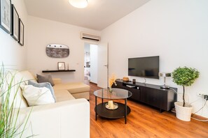 Ein modernes Wohnzimmer mit einer Couch, einem Couchtisch, einem Fernseher und einer kleinen Pflanze.