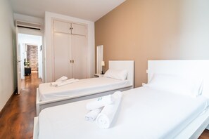 A hotel room with two single beds, a wardrobe, a bedside table with a lamp, and a bathroom visible through an open door. - Cubo's Montaño Malaga Apartment / near beach / urban / air conditioning / free wifi (Málaga)