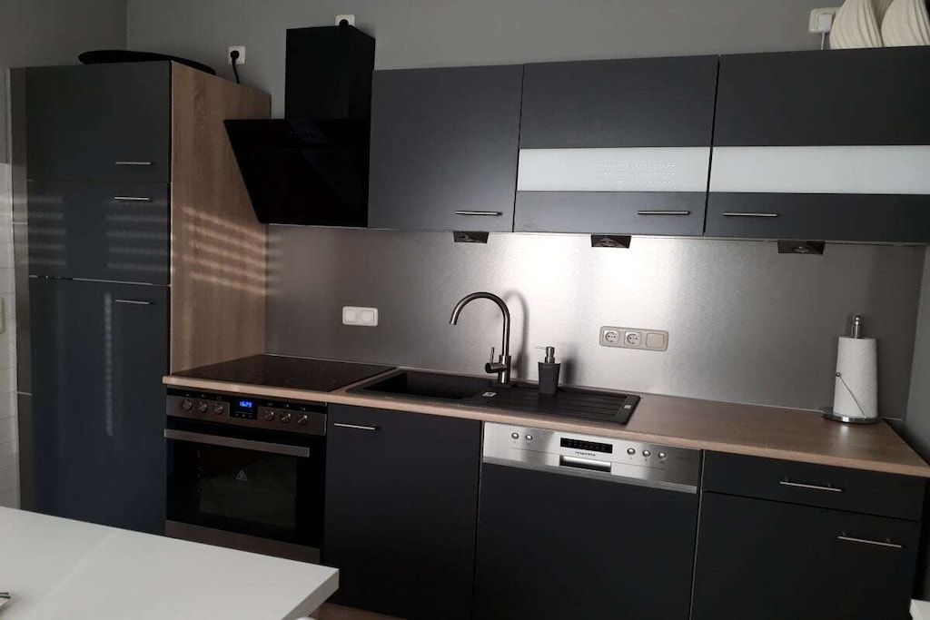 Eine moderne Küche mit Backofen, Geschirrspüler und einer Edelstahl-Spüle.