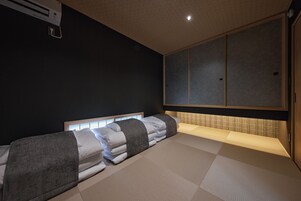 Una habitación con una cama, una camilla de masaje y un amplio ventanal corredero.