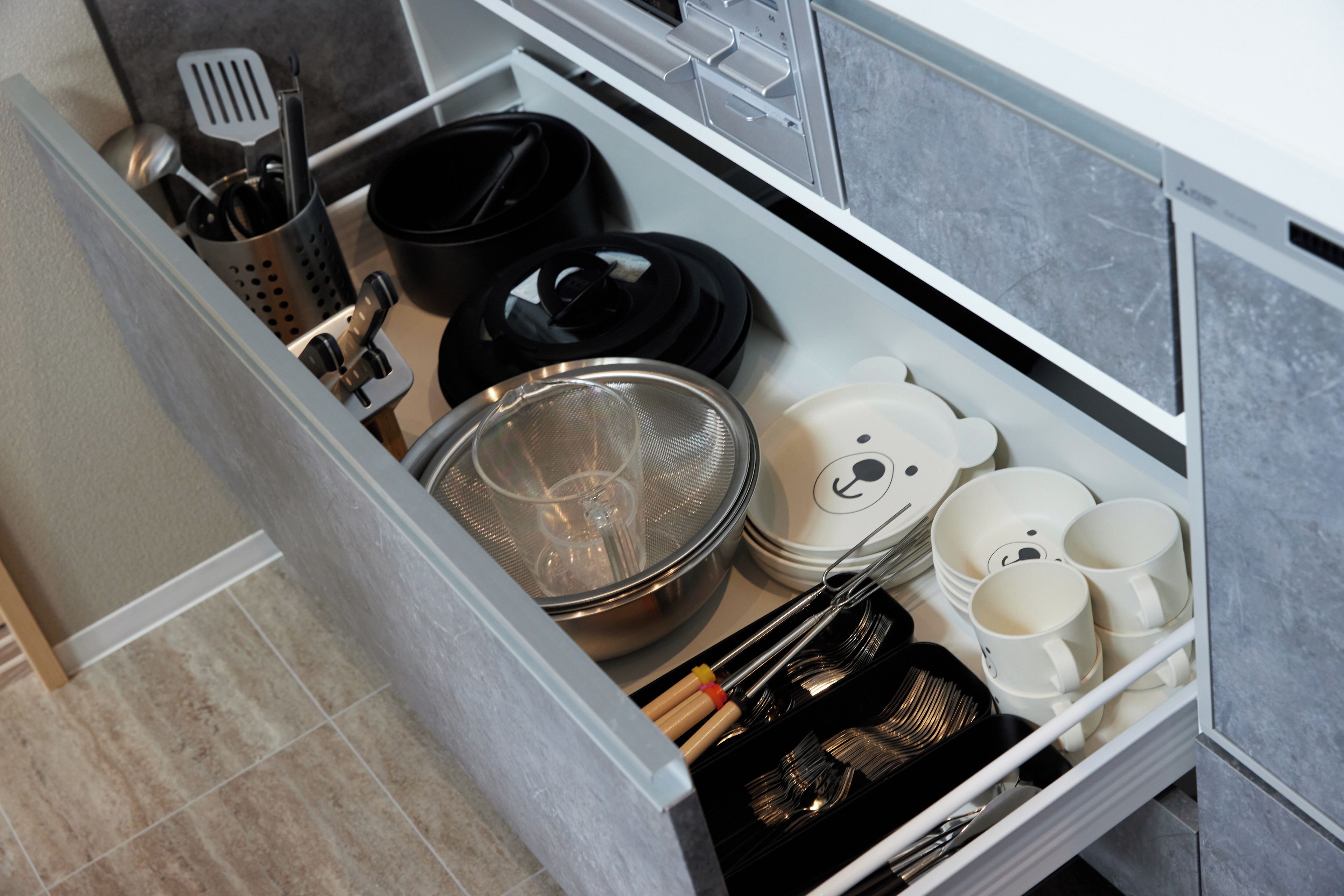 A kitchen drawer with utensils, cookware, and plates.