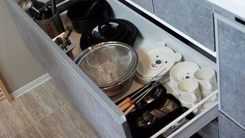 A kitchen drawer with utensils, cookware, and plates.