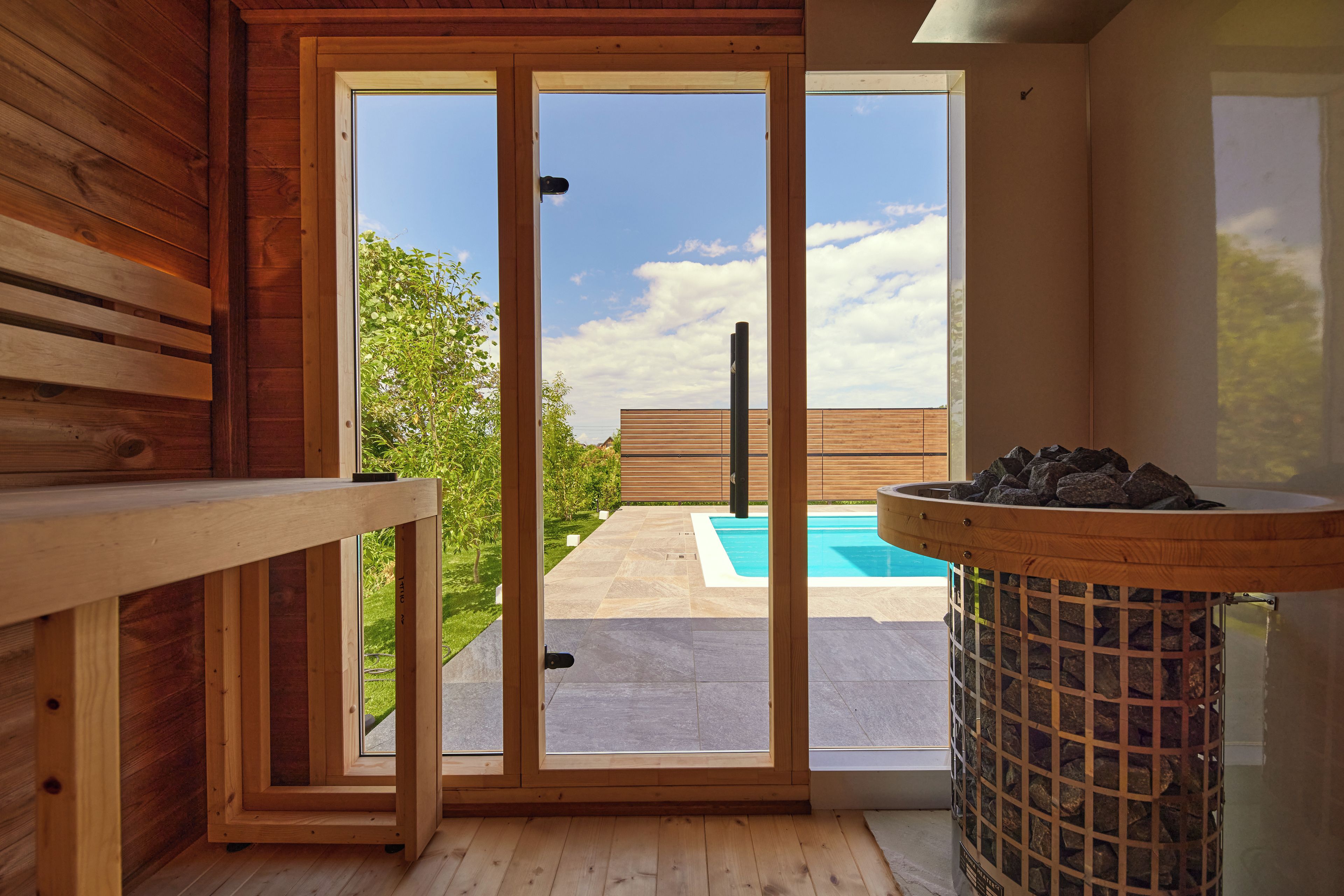 Un intérieur en bois avec une porte-fenêtre coulissante donnant accès à un espace piscine extérieur.