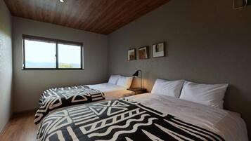 A bedroom with a large bed, a smaller bed, and a window with a view.