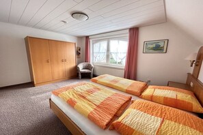 A bedroom with a bed, a wardrobe, a chair, and a window with curtains. - Holiday home Johren Apt. 2 (Norderney)