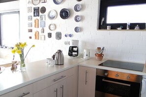 Eine Küche mit weißen Schränken, einer Kaffeemaschine, einem Toaster und verschiedenen dekorativen Tellern an der Wand.