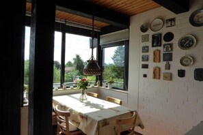 A dining area with a table set for four, a hanging light fixture, and a wall adorned with various decorative plates and items. - Wagner House - Schleiblick Lindaunis (Boren LIndaunis)