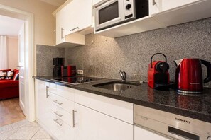 A modern kitchen with white cabinets, a granite countertop, a Siemens microwave, a red kettle, and a coffee maker. - No. 9 in Villa Aegir (Ostseebad Binz)