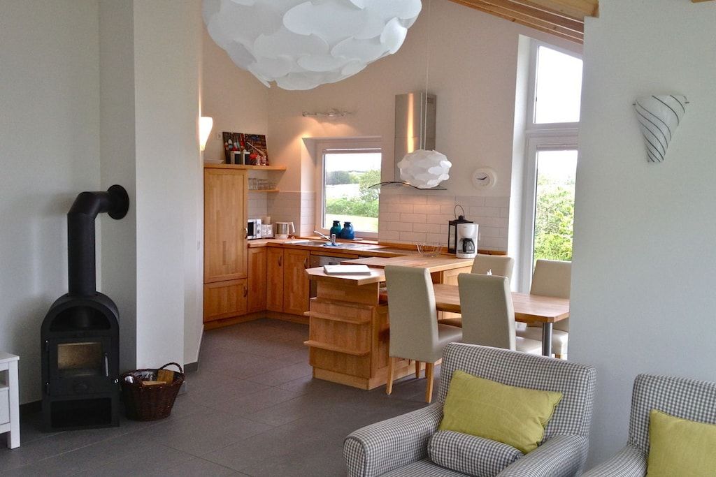A modern kitchen with a central island, wooden cabinets, and a built-in stove.
