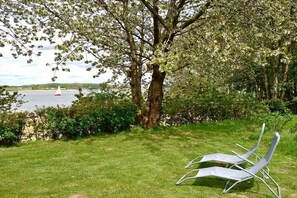 A grassy area with a tree and a white lounge chair. - Holiday home in Kosel with swimming pool (Kosel)