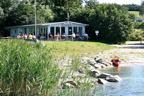 A building with a sign reading 'HafenCafé' with people seated outside. - Marina Hülsen - Skipper Lodge South (Kosel)