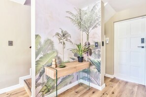 Ein Flur mit einem Holzkonsolentisch, einem Blumentopf und einer Tür mit Lichtschalter.