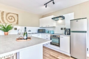 Eine moderne Küche mit weißen Schränken, einem eingebauten Ofen, einer Mikrowelle und einem Edelstahl-Kühlschrank.