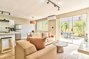 A modern living room with a sofa, coffee table, and dining area. - Stunning 2-Bed Duplex with Air-Con, Close to Beach, Cafés & Restaurants (Cape Town)
