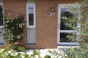 A brick building with the number 28, a door, and a window. - Holiday home in Kosel with swimming pool (Kosel)