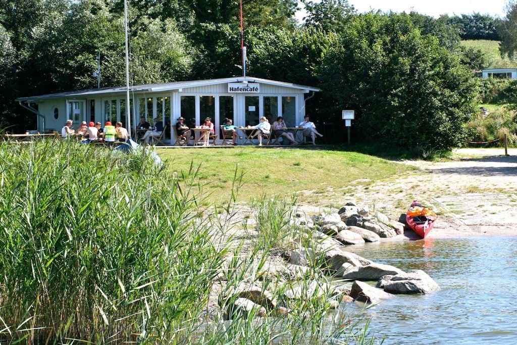 A building with a sign reading 'HafenCafé' with people seated outside.