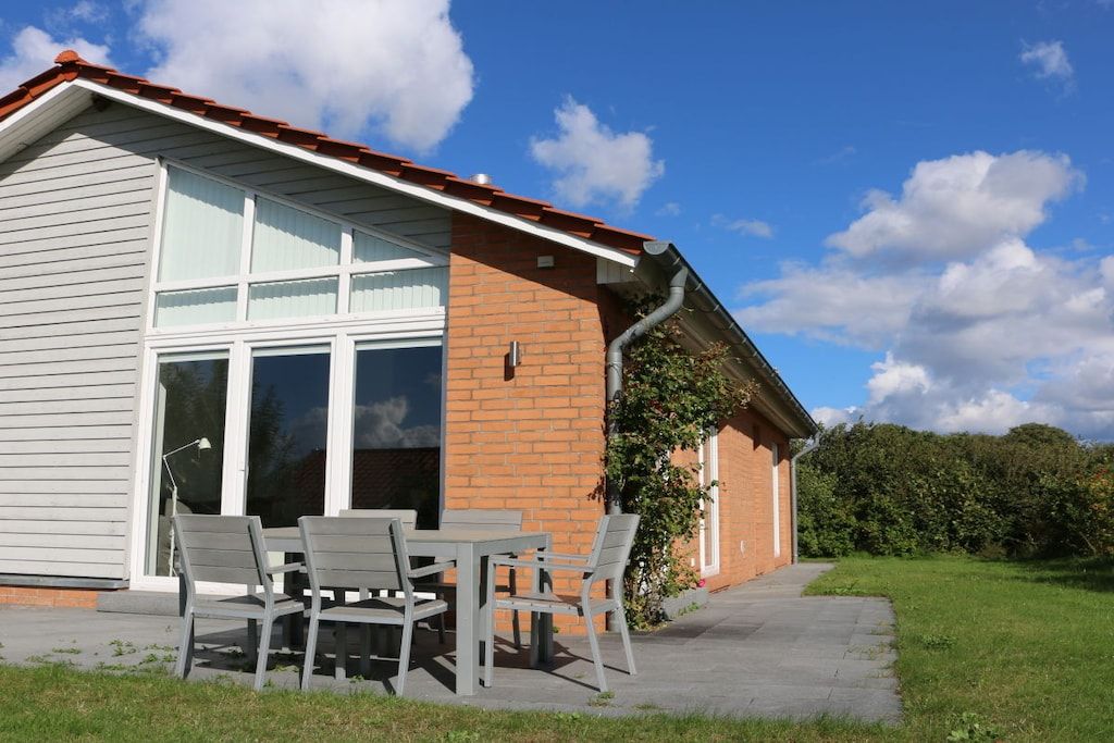 A building with a brick exterior, large windows, and a patio with outdoor furniture.