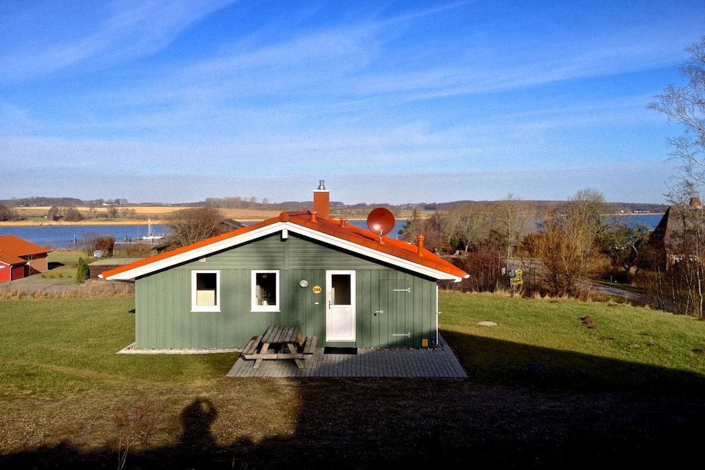 Een groen gebouw met een rood dak, een schotelantenne en een picknicktafel ervoor.