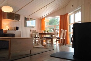 Un salon confortable avec un canapé, une table à manger et des chaises, un téléviseur et une fenêtre avec des rideaux.