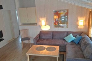 A living room with a sofa, a coffee table, a cabinet, and wall-mounted lights. - Marina Hülsen - Skipper Lodge North (Kosel)