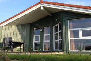 A green building with a red roof, large windows, and outdoor seating. - Marina Hülsen - Skipper Lodge North (Kosel)