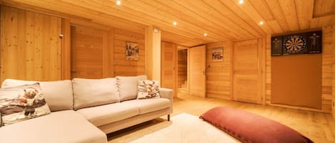 Ein gemütliches Zimmer mit einer Couch, einem roten Kissen, Holzwänden und einer Dartscheibe.