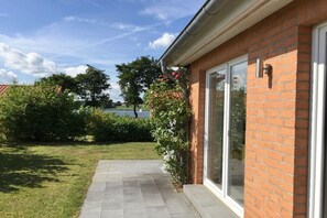 A brick building with a glass door and a pathway leading to a grassy area. - Holiday home in Kosel with swimming pool (Kosel)