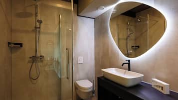 Un baño moderno con ducha envuelta en vidrio, inodoro y tocador con un espejo grande.