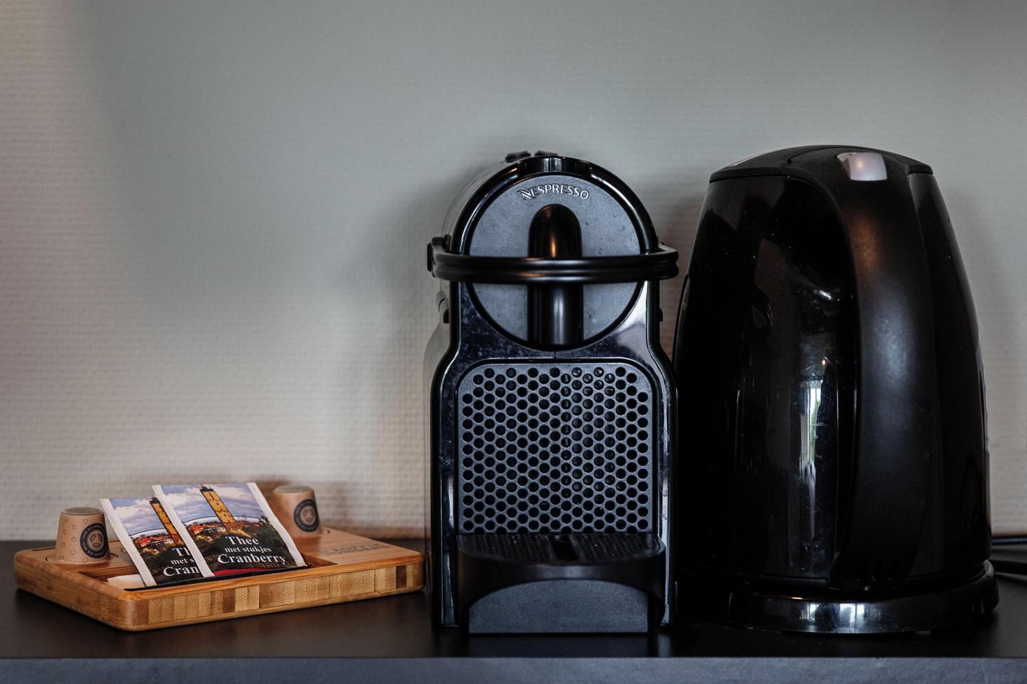 Eine Nespresso-Kaffeemaschine und ein Kaffeekännchen stehen auf einer Arbeitsplatte.