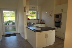 Eine moderne Küche mit weißen Schränken, einer schwarzen Arbeitsplatte und einem eingebauten Backofen.