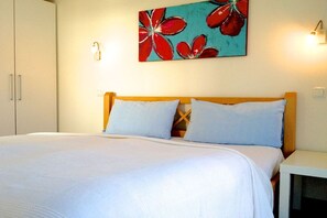 Ein Bett mit weißer Bettwäsche, einem hölzernen Kopfteil und zwei Kissen.
