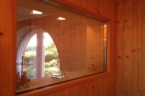 Ein Holzinnenraum mit einem großen Bogenfenster, einer klaren Glasfläche und einem sichtbaren Kreuz.