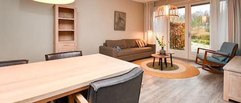 Una sala de estar moderna con una mesa de comedor de madera, un sofá, una silla y una lámpara.