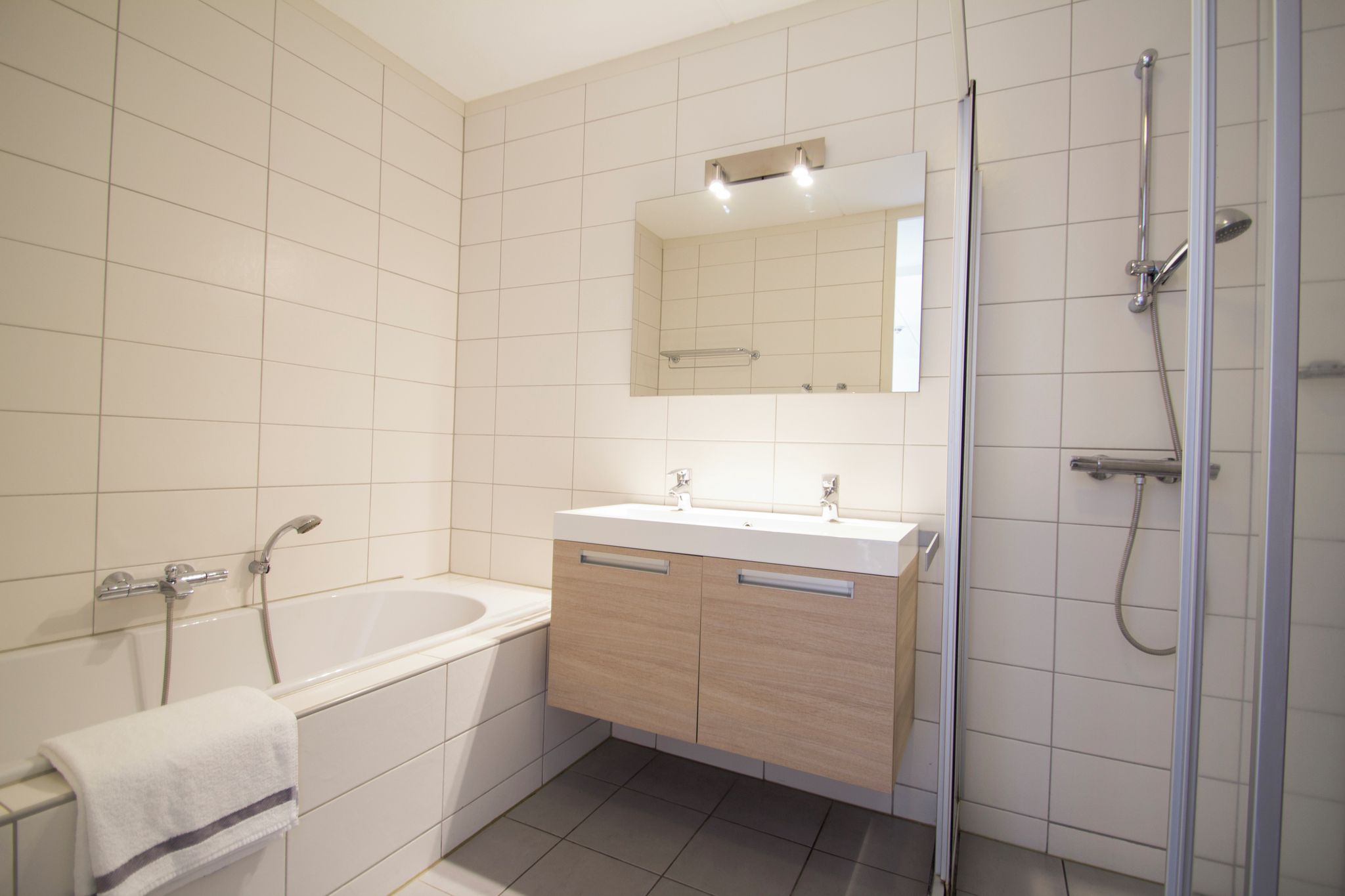 Une salle de bain moderne avec une baignoire, un lavabo avec un miroir au-dessus et un espace douche.