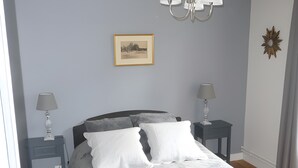 Ein Schlafzimmer mit einem Bett, zwei Nachttischen, einer Chandelierleuchte, einem gerahmten Bild und einem Wanddekor.