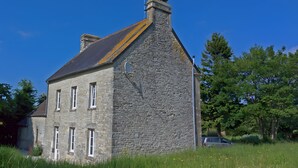 Ein Haus aus Stein mit einem steilen Dach, vielen Fenstern und einem Schornstein.