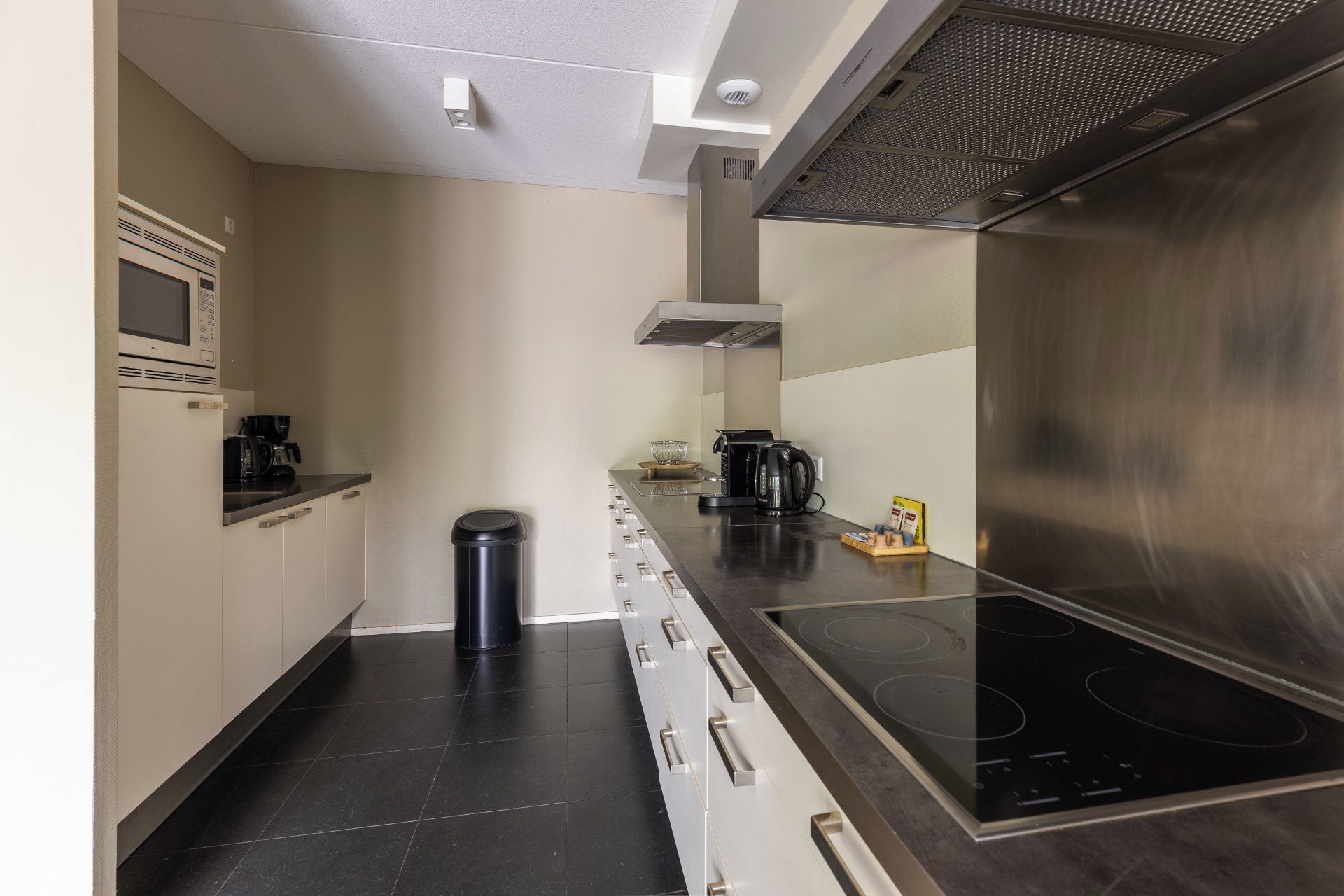 Una cucina moderna con piano cottura integrato, forno a microonde e macchina da caffè.