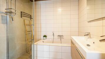 A modern bathroom with a glass shower enclosure, a wooden ladder, a bathtub, and a white sink with a mirror.